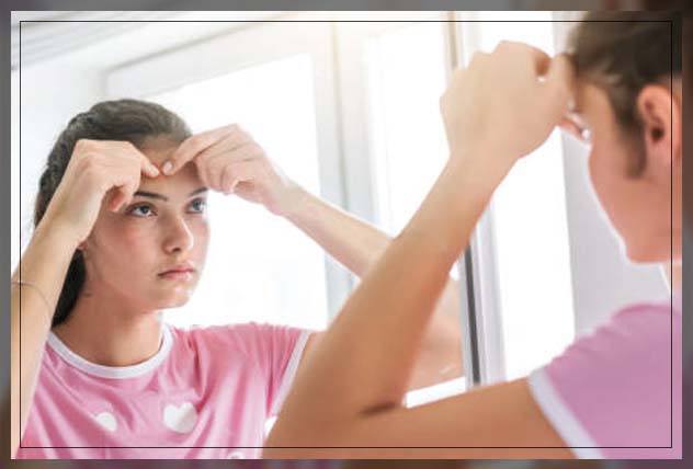 woman popping pimple on her forehead